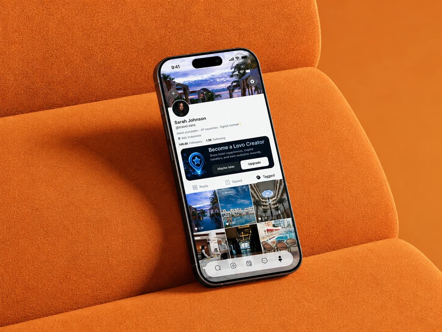 Lovo creator profile with a Become a Lovo Creator banner, on a phone lying on an orange sofa