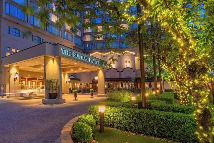 Hotel entrance framed by trees strung with lights at dusk