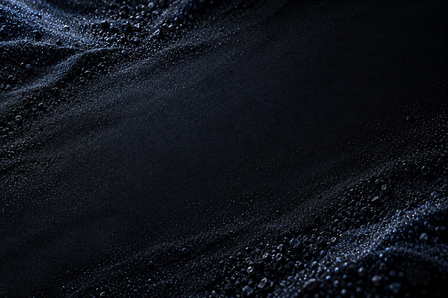 Dark sand with beads of silver light.